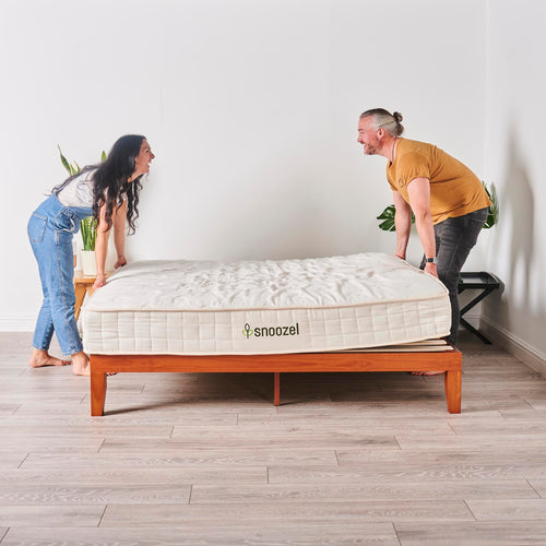 Smiling couple set up their new snoozel green matter on a wooden bed frame